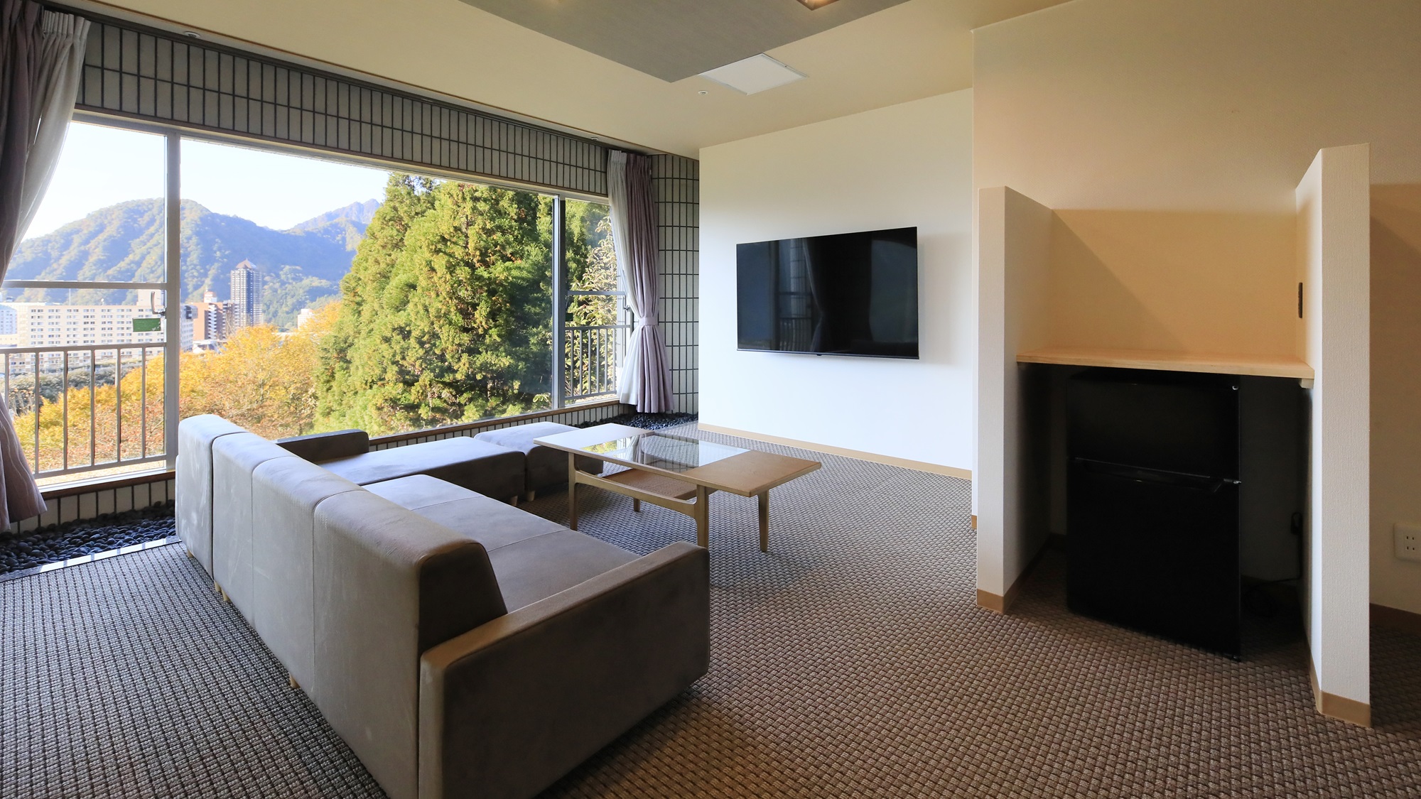 温泉内風呂付き和洋室｜大きな窓から越後湯沢の山並みを一望できる、開放感あふれるリビング