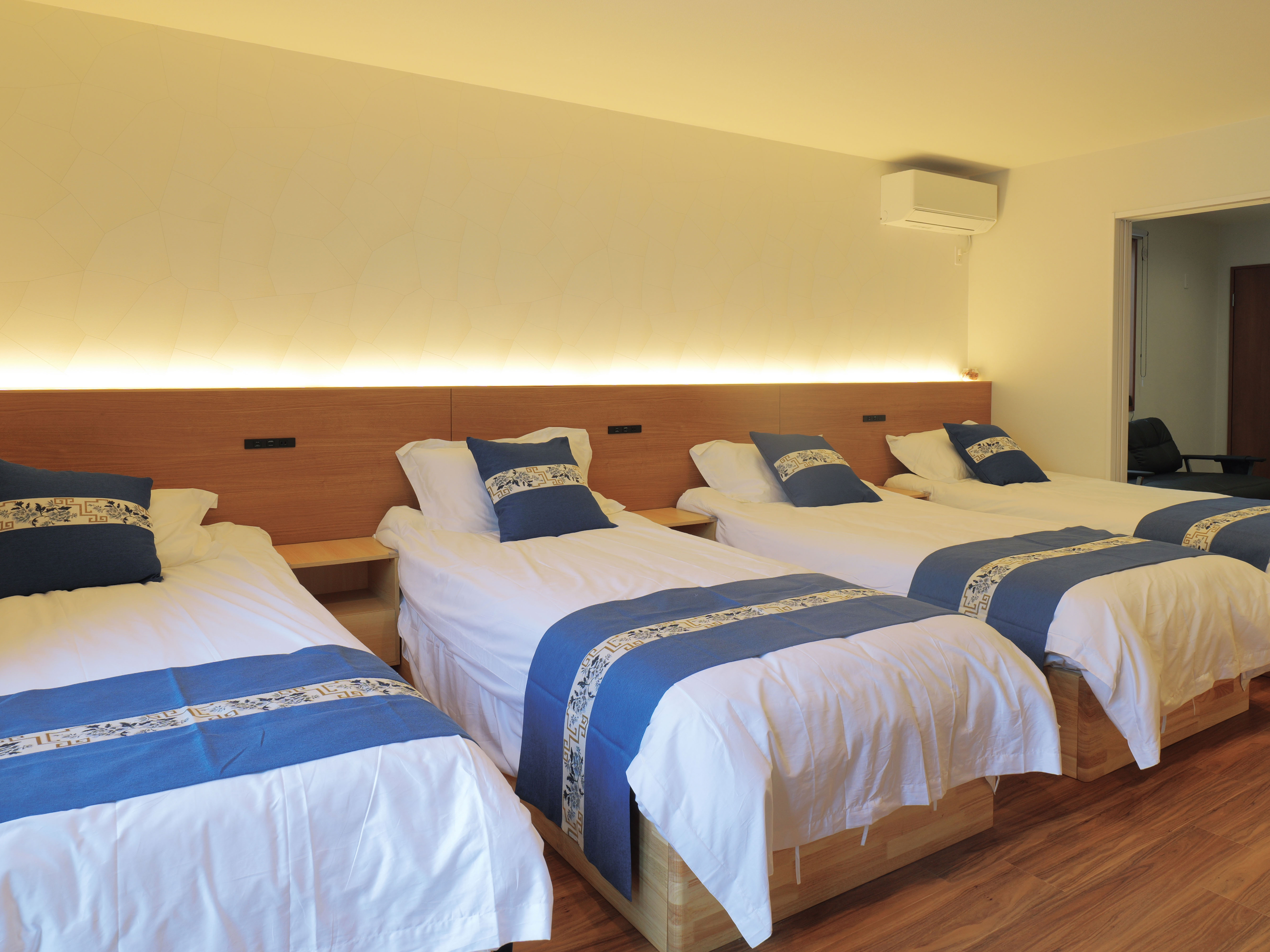 広々とした当施設のお部屋は、 シングルベッド4台＋ソファベッド1台（ダブルサイズ） を備えており、 最大で6名様までご宿泊可能です。ご家族やご友人同士のご旅行に最適です。  お部屋には独立したバスルーム・トイレを完備し、 快適にお過ごしいただけるよう設備を充実させております。 ミニキッチン・電子レンジ・冷蔵庫のほか、 最新のパナソニック製乾燥機能付き洗濯機もご用意しており、 長期滞在やファミリー旅行にも大変便利です。  木目調の温かみあるデザインとやわらかな照明で、 ゆったりとおくつろぎいただける空間となっております。