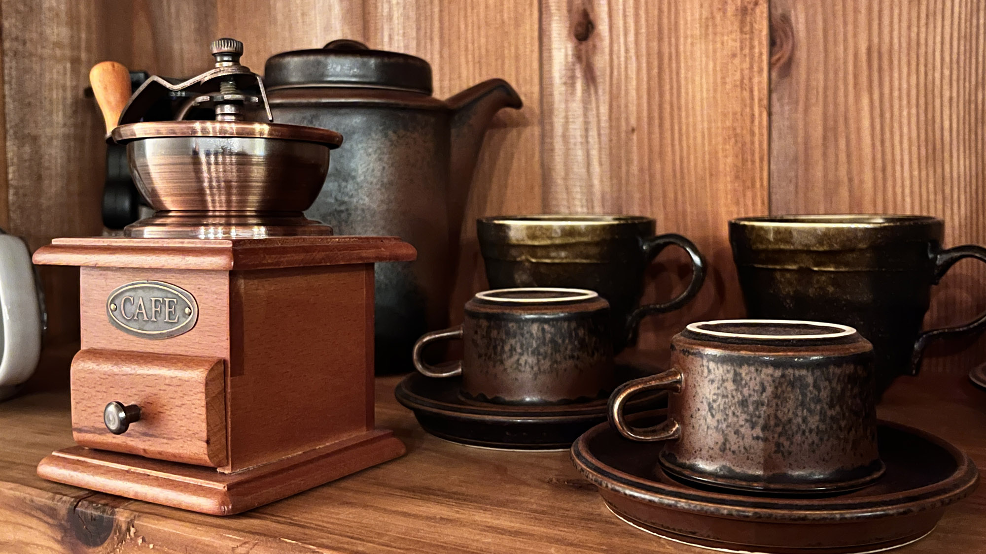 【イメージ】手挽きミルと温かみのある器が並ぶ棚。ここでのコーヒーは、特別に感じる味わい。