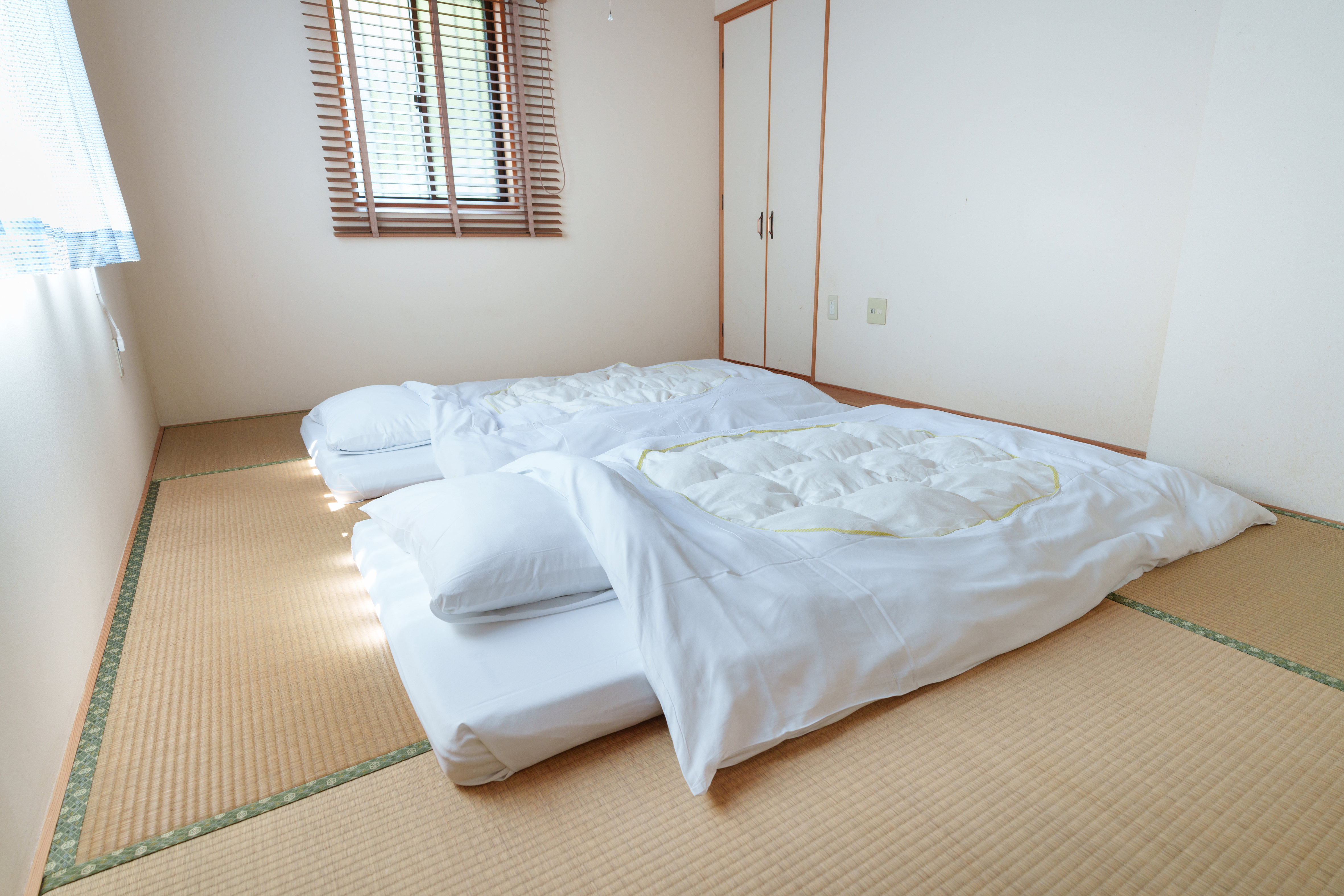 ブラインド越しに差し込む朝光が、畳の上に穏やかな紋様を描き出す。清潔なリネンに身を包み、い草の香りを深く吸い込めば、旅の疲れが静かに溶け出していくのを感じるはずです。装飾を削ぎ落としたからこそ際立つ、静寂という名のおもてなし。