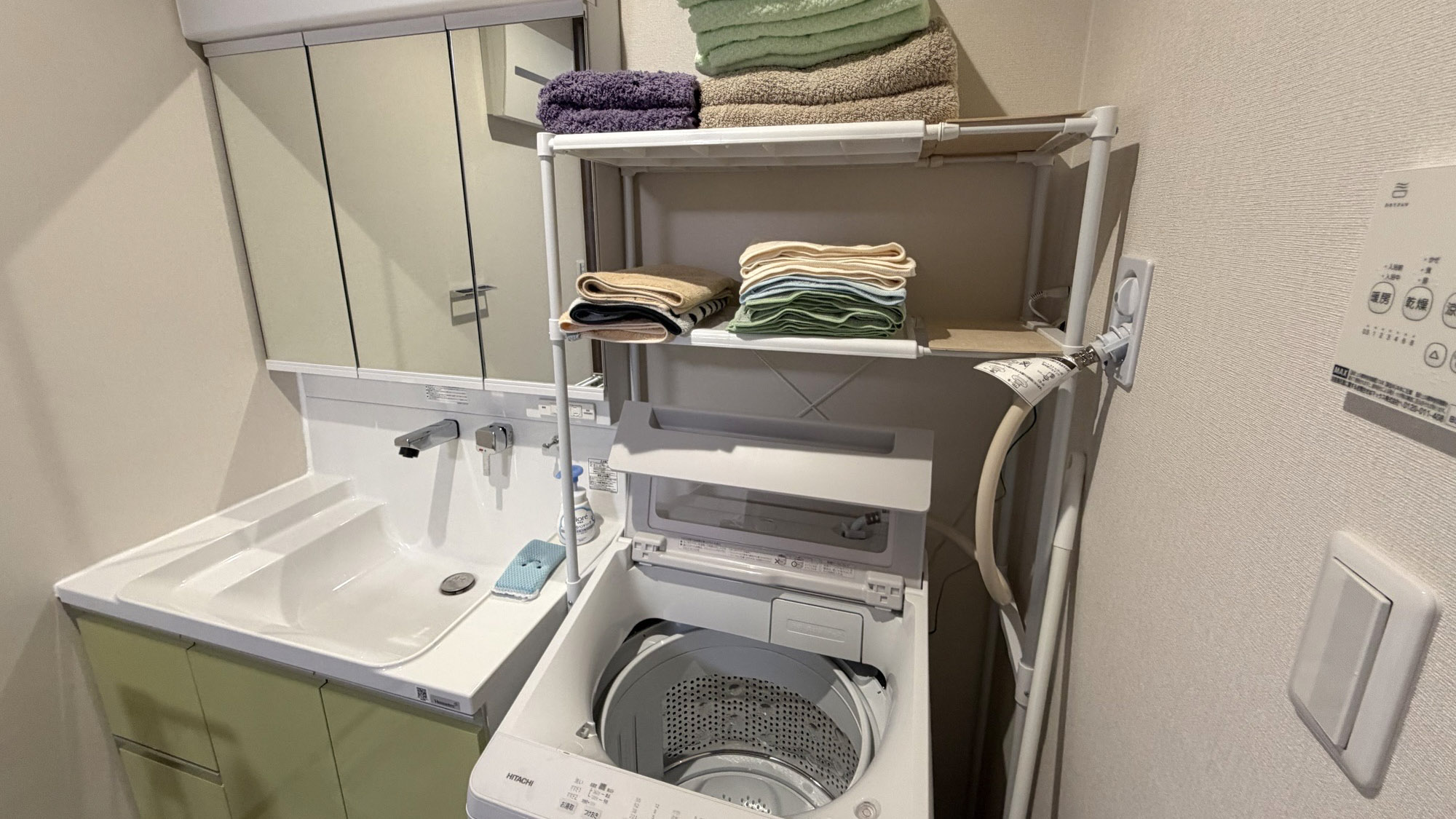 ・【洗面所／ランドリー】三面鏡付き洗面台と長期滞在にも便利な洗濯機やタオル類がございます
