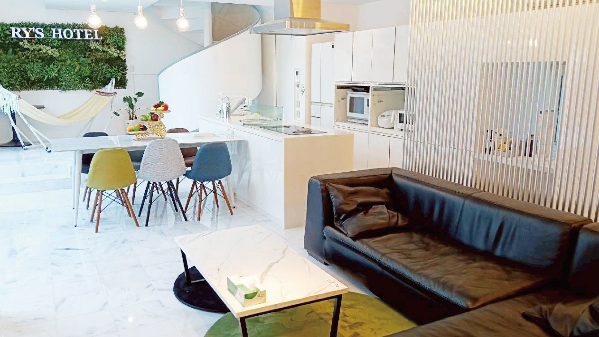 白を基調とした明るく開放的なリビングダイニング。 広々としたダイニングテーブルとモダンなキッチンを備え、グループでの食事や団らんの時間をゆったり楽しめます。 室内には当ホテルのモニュメントとハンモックもあり、非日常のリラックス空間を演出しています。