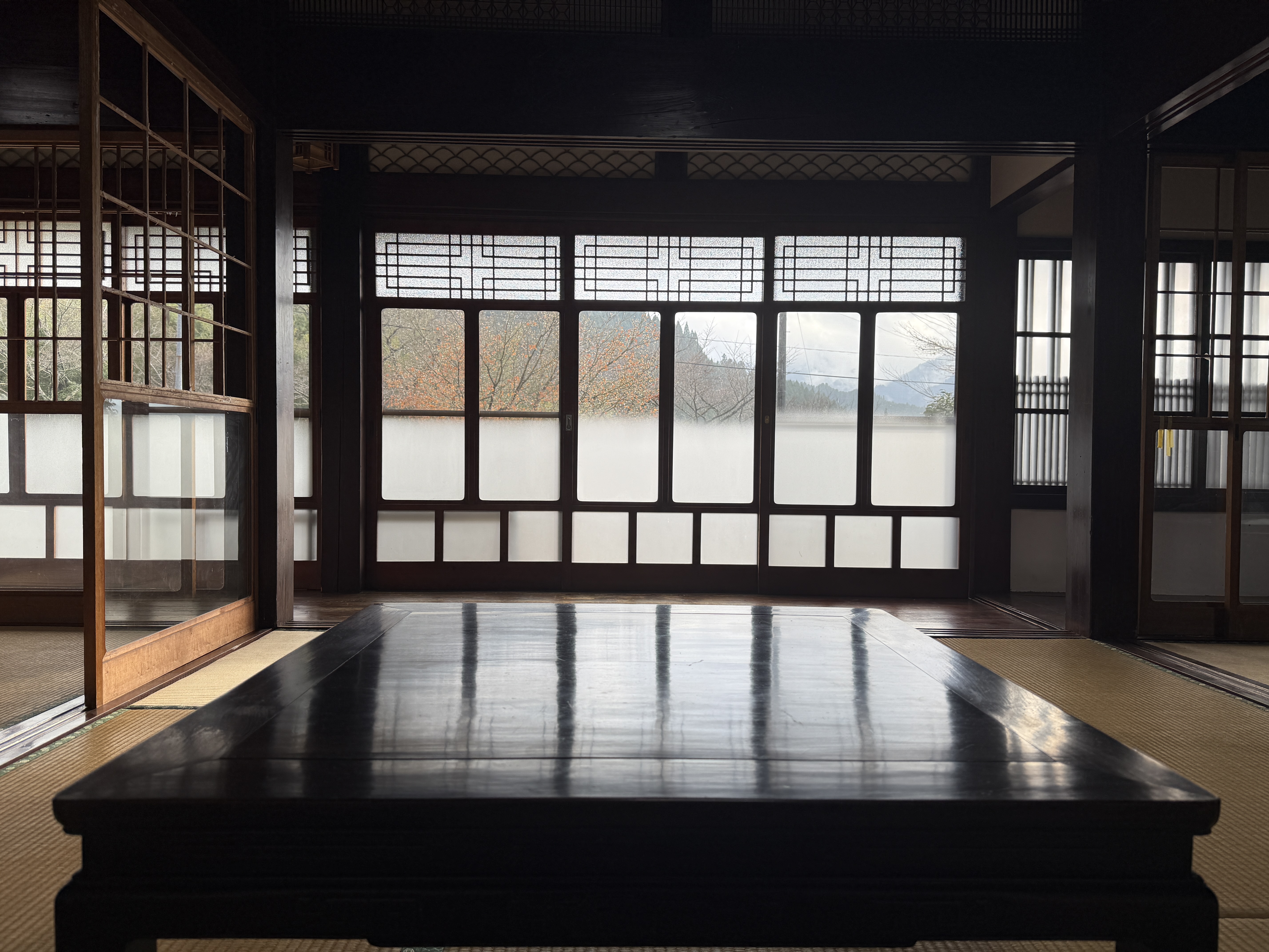 広間から縁側越しに山々を望む。夕暮れ時に和室に差し込む光はあたたかく、黒檀のテーブルが光を反射させ唯一無二の空間を演出します♪