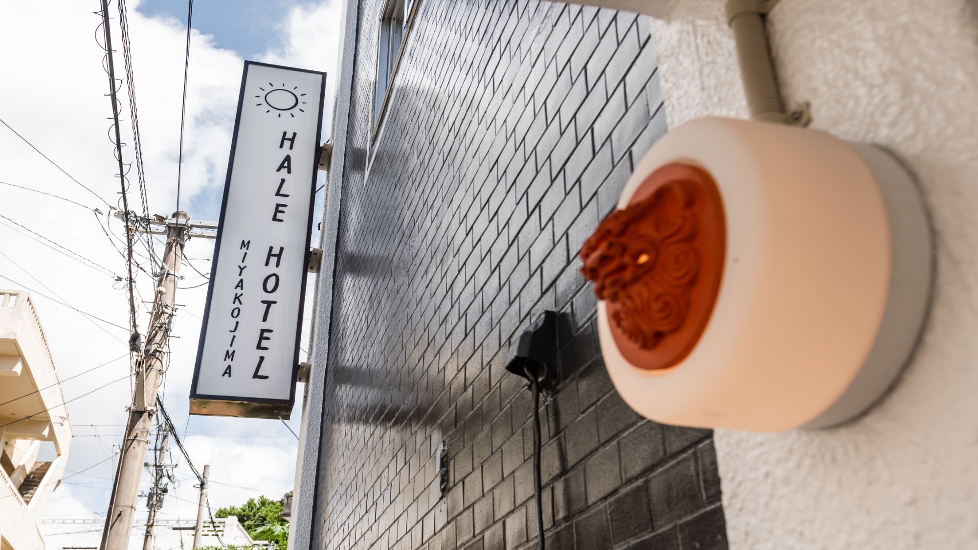 【外観】ホテルロゴとシーサーが目印。明るく清潔感のある入り口で、皆様を温かくお迎えします。