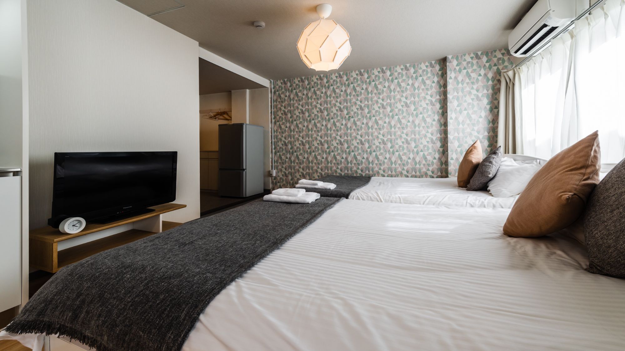 【ツインルーム（キッチン・シャワー・トイレ付）205室】テレビを眺めながらベッドの上でリラックスタイ