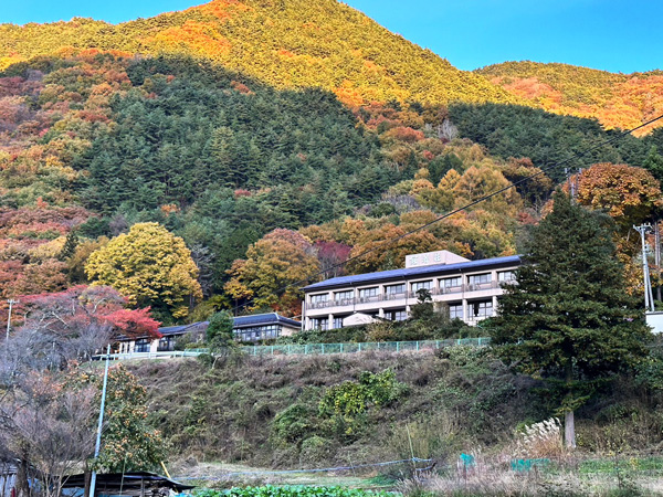 色づいた山あいに溶け込むように建つ冠着荘の全景。四季折々の自然に囲まれた、静かな環境が魅力です。