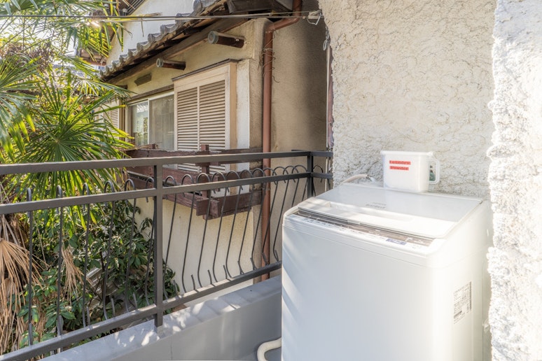 ２階のベランダにある洗濯機と洗濯用洗剤