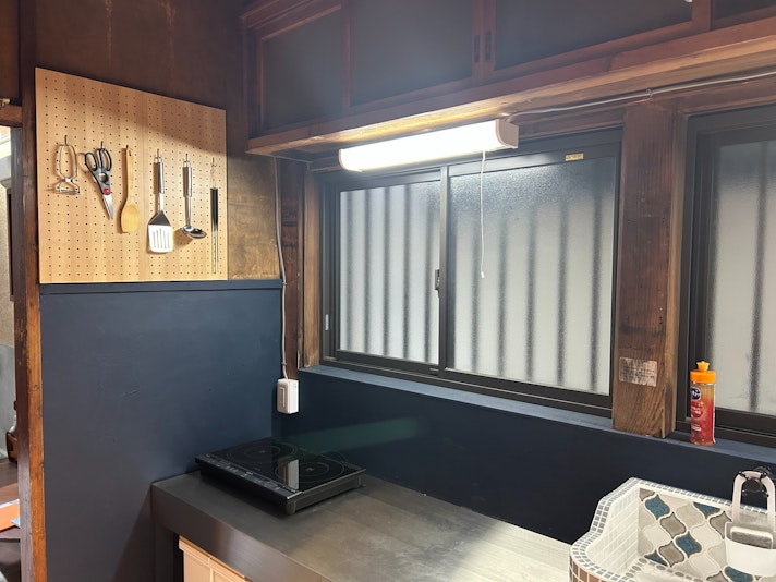 木目調の有孔ボードに、料理道具が整然と掛けられたこの光景は、どこか懐かしくも温かみのある台所の一角を