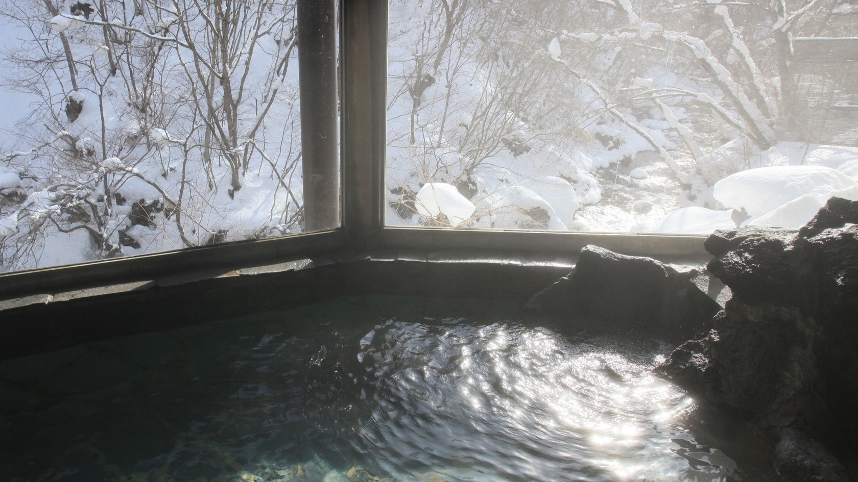 【岩風呂／涼風と岩の湯（男女入替制）】朝の光で輝く、美しい雪と温泉