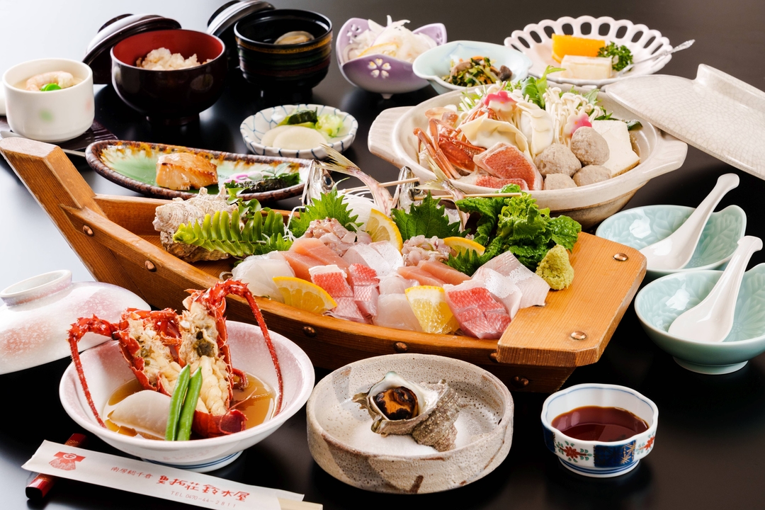 魚拓荘鈴木屋の夕食。舟盛りに伊勢海老とあわびが並ぶ磯料理の膳