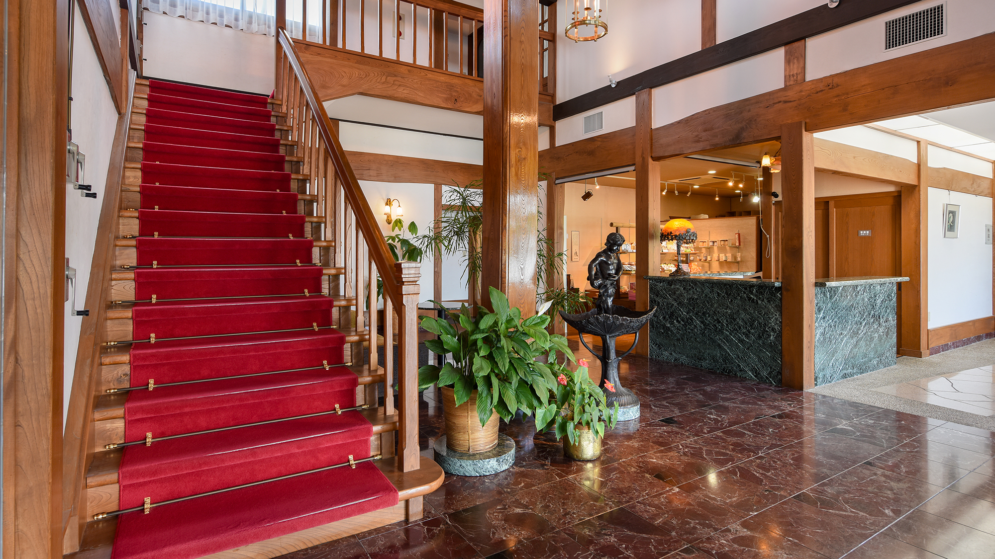 【フロント・ロビー】欅造りのロビー。2階へと続く赤い絨毯の階段が印象的。