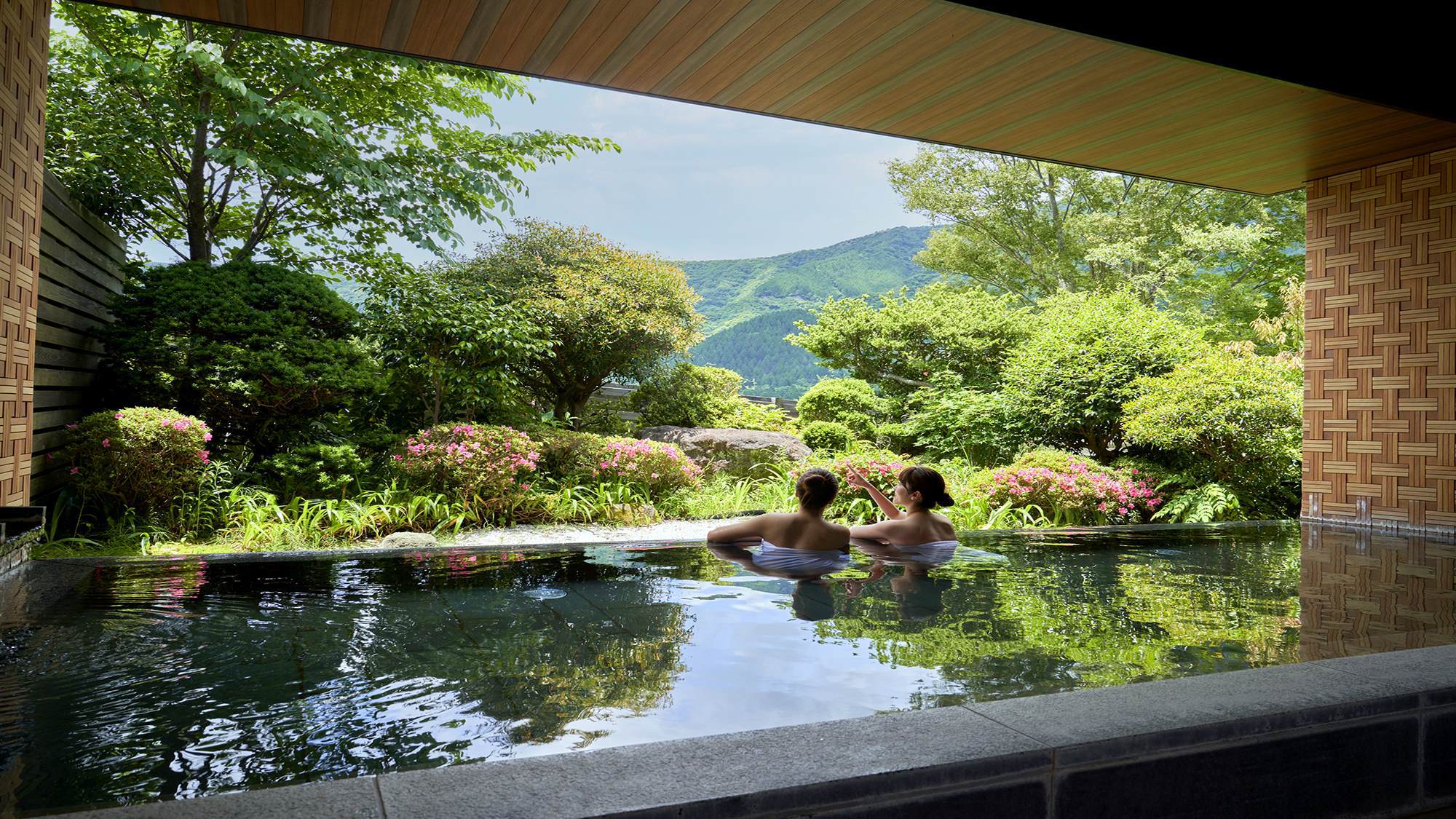 【露天風呂・昼】雄大な箱根外輪山の眺望が楽しめ、箱根寄木細工をテーマとした壁面が特徴的です。