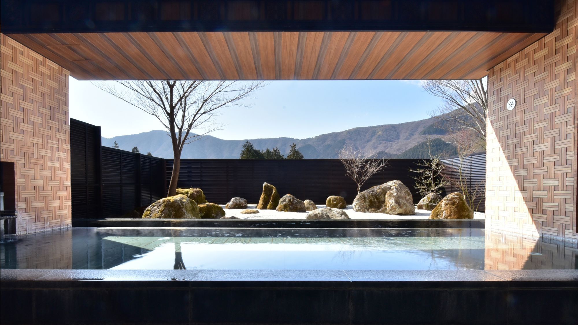 【露天風呂】2025年3月1日庭園を枯山水にリニューアル。箱根寄木細工をモチーフとした壁面が特徴的。