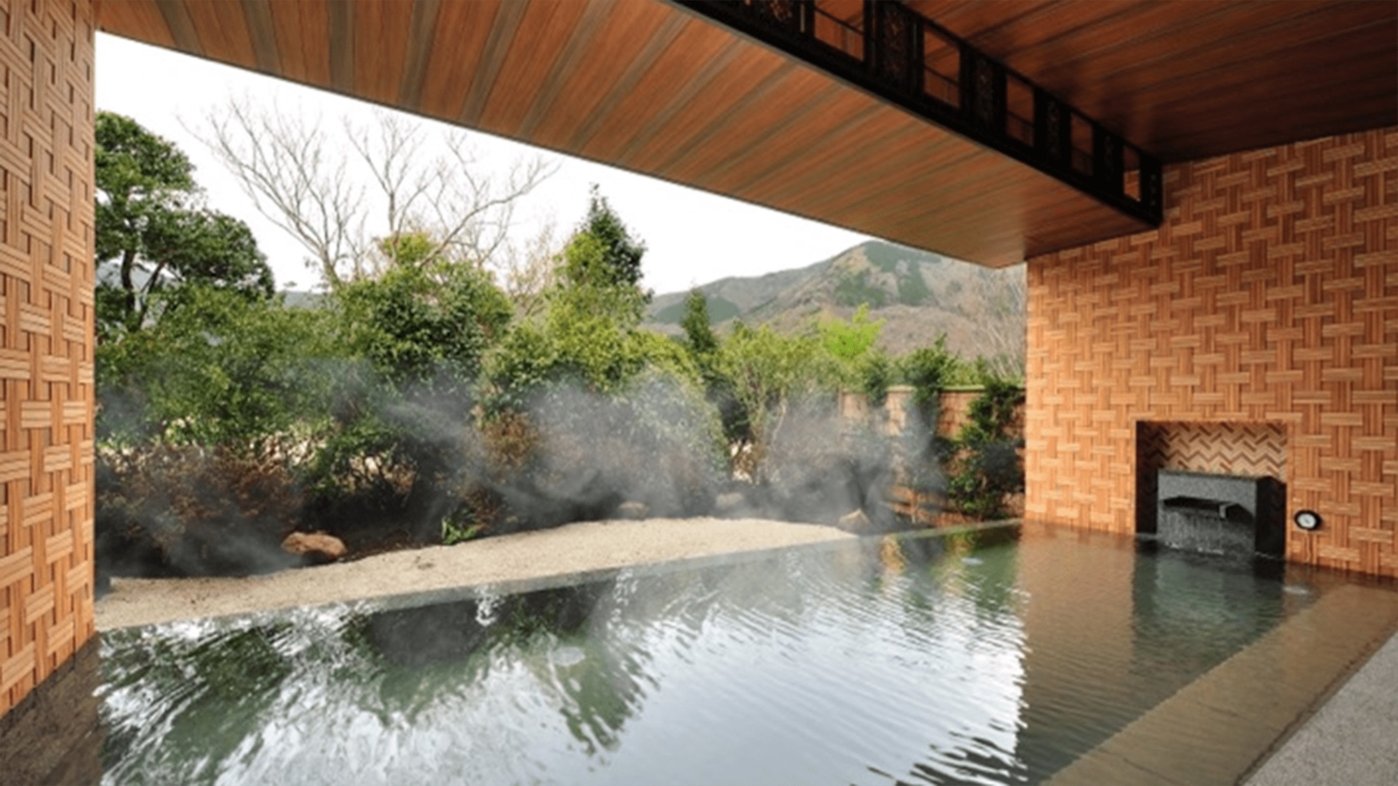 【露天風呂・昼】雄大な箱根外輪山の眺望が楽しめ、箱根寄木細工をモチーフとした壁面が特徴的です。