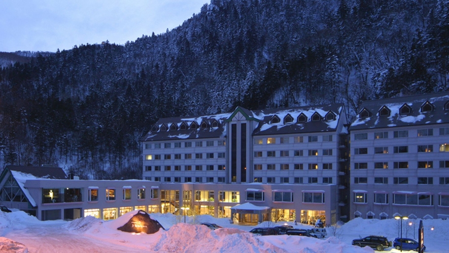 【外観】雪景色の峡谷をバックにライトアップされた朝陽リゾートホテル（12月～3月頃）