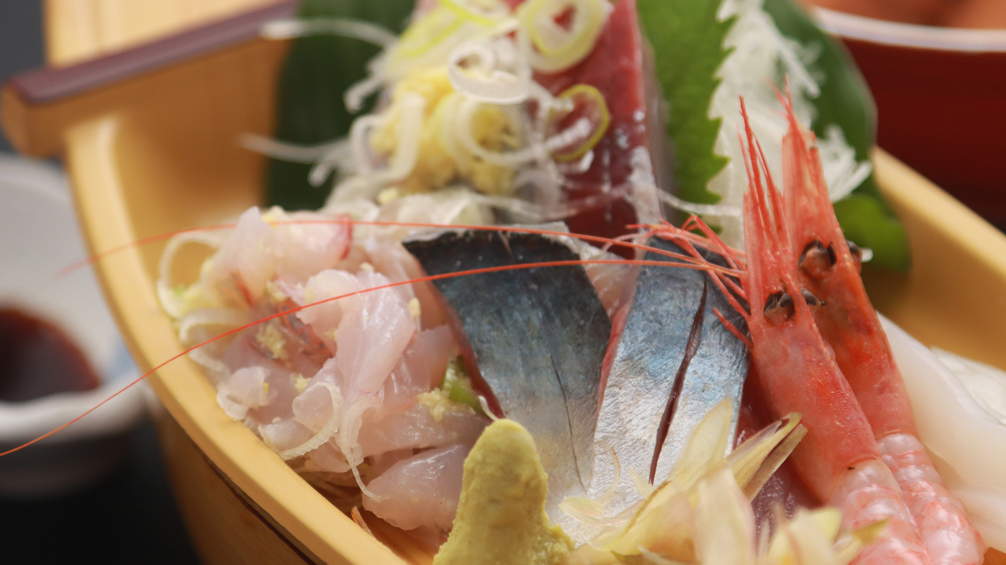 能登 島宿せがわの夕食。舟形の器に盛った刺身と煮魚が並ぶ会席