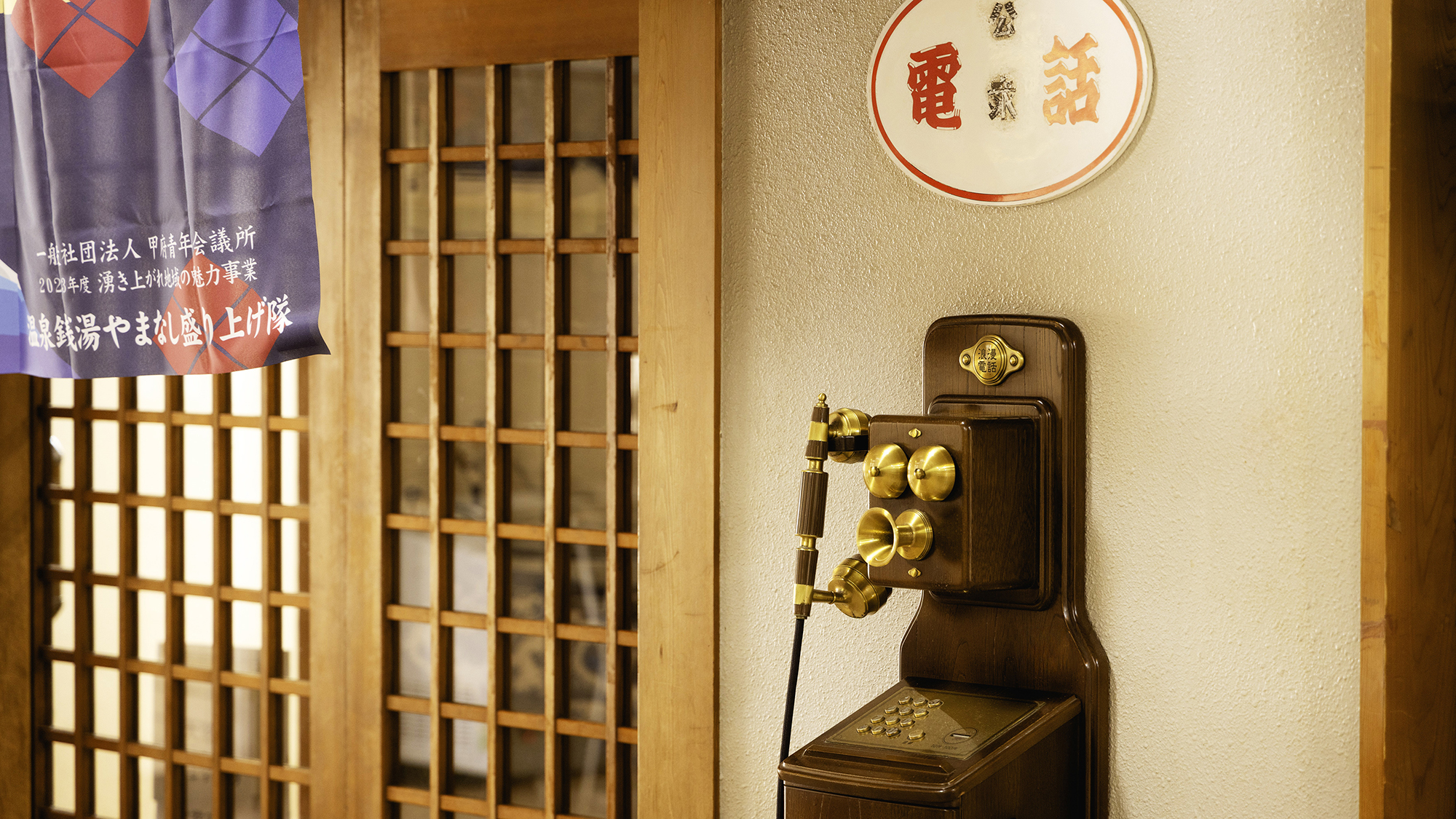 【大浴場入口】大浴場へと続く館内。レトロな電話は今もご利用いただけます