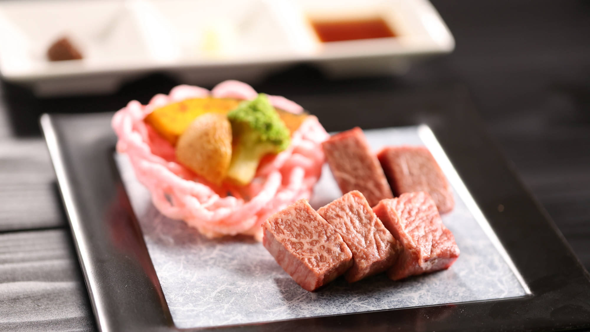 【強肴】美しいサシが入った厳選和牛のステーキ。一口サイズで香ばしく焼き上げ、お好みの薬味やタレととも