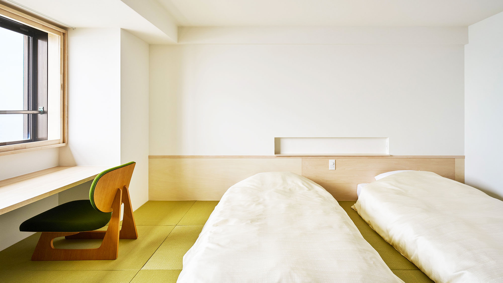 【新装和洋室ツイン】ワーケーション対応：琉球畳の上に置かれたシモンズ製のローベッド2台を配置。