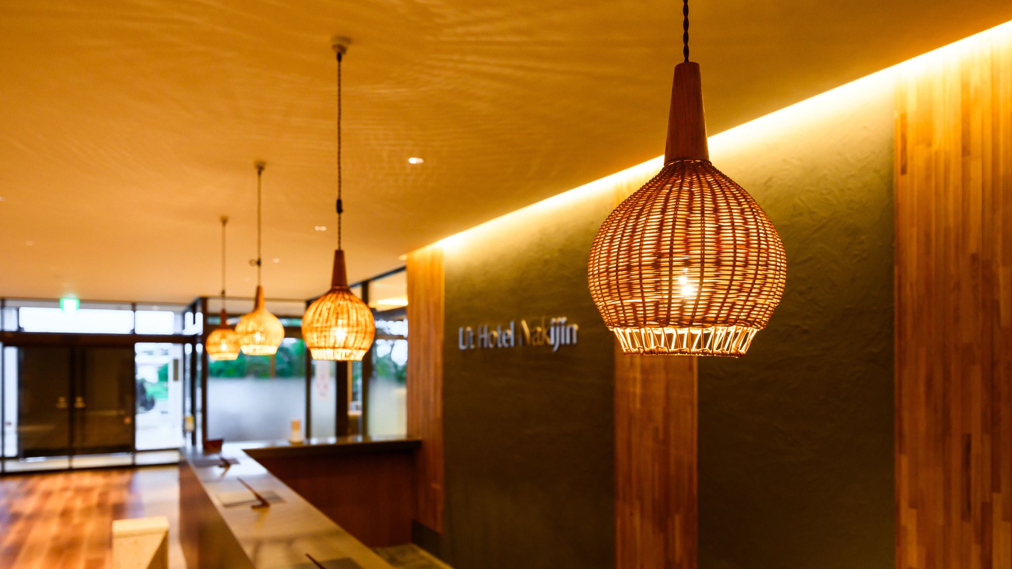 【フロント/ロビー】柔らかな照明と木目が心地よい空間。洗練された新しいホテルロビー。