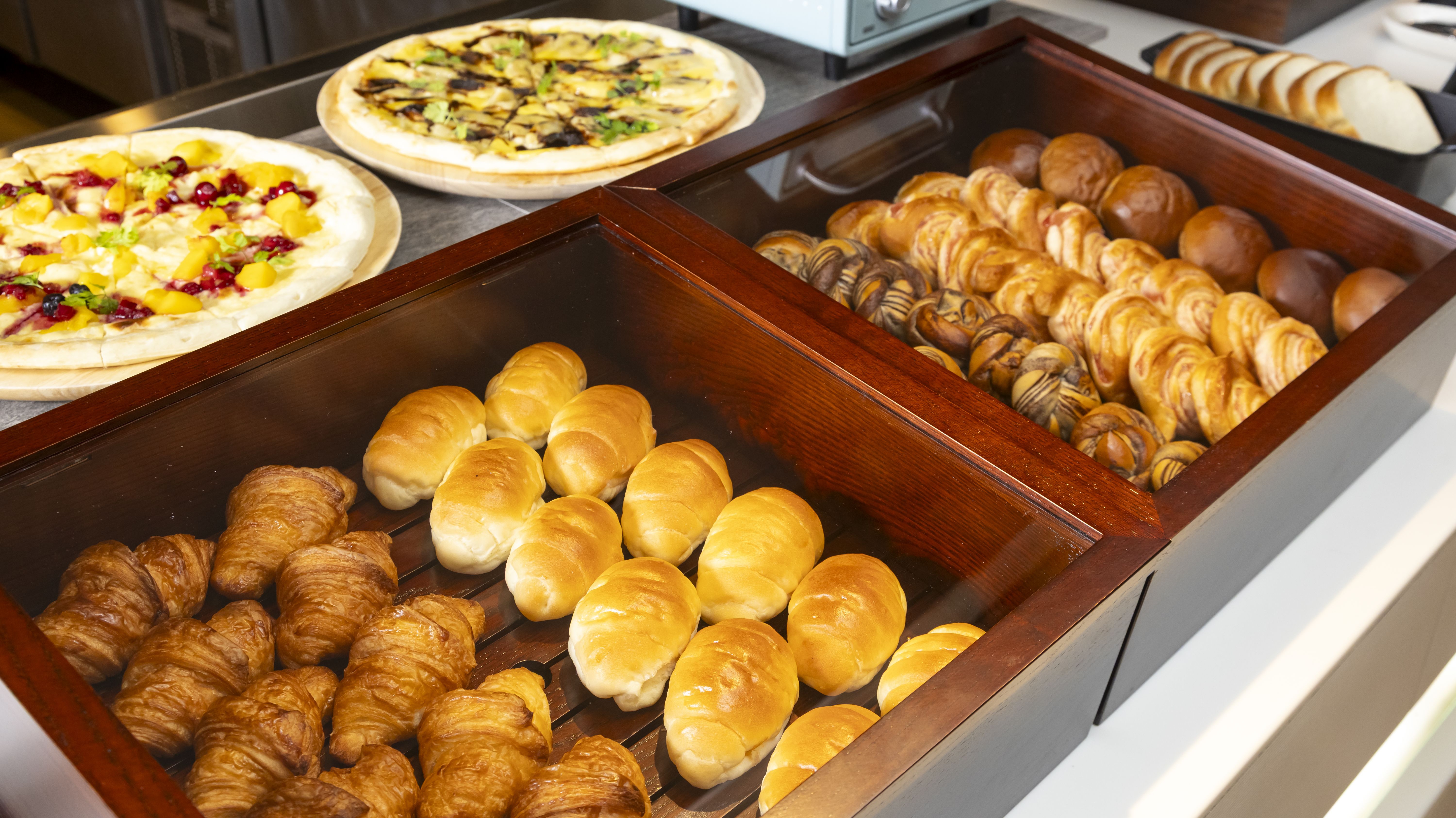 朝食ビュッフェ／パンコーナーには数種類のパンやピザが並びます（イメージ）