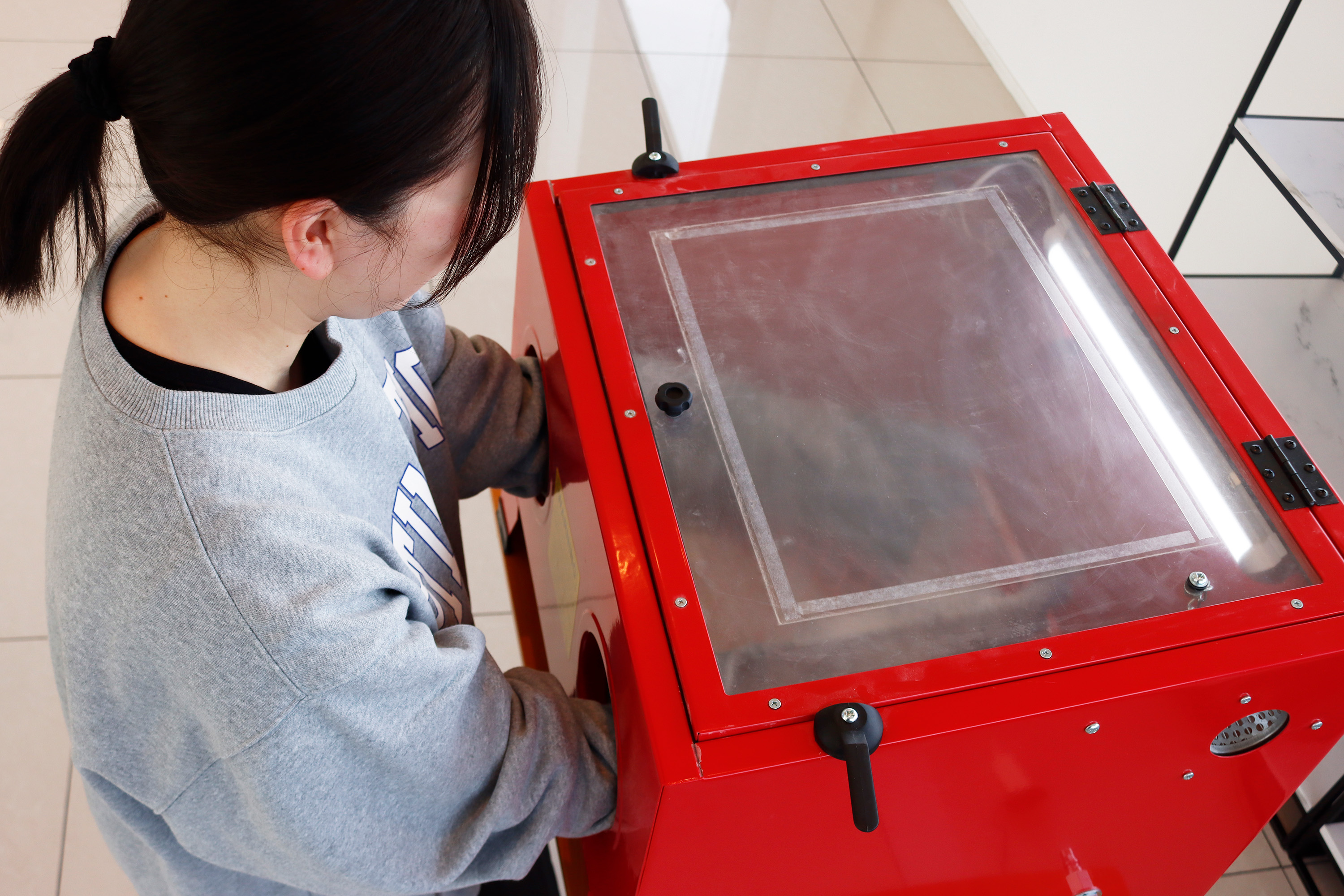 サンドブラストマシーンでグラスに貼り付けた模様を吹き付けます