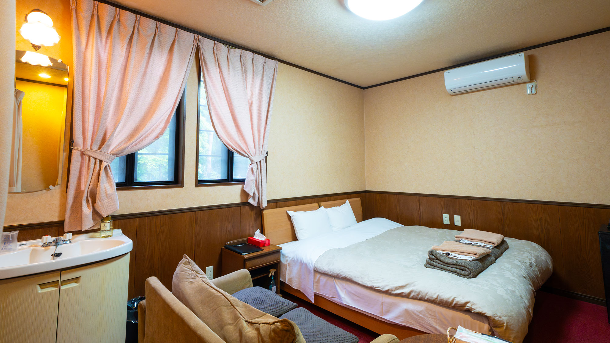 【メイン館2階／テラス露天風呂付客室】ベッド・ソファーセット・洗面台がコンパクトにまとまっています。