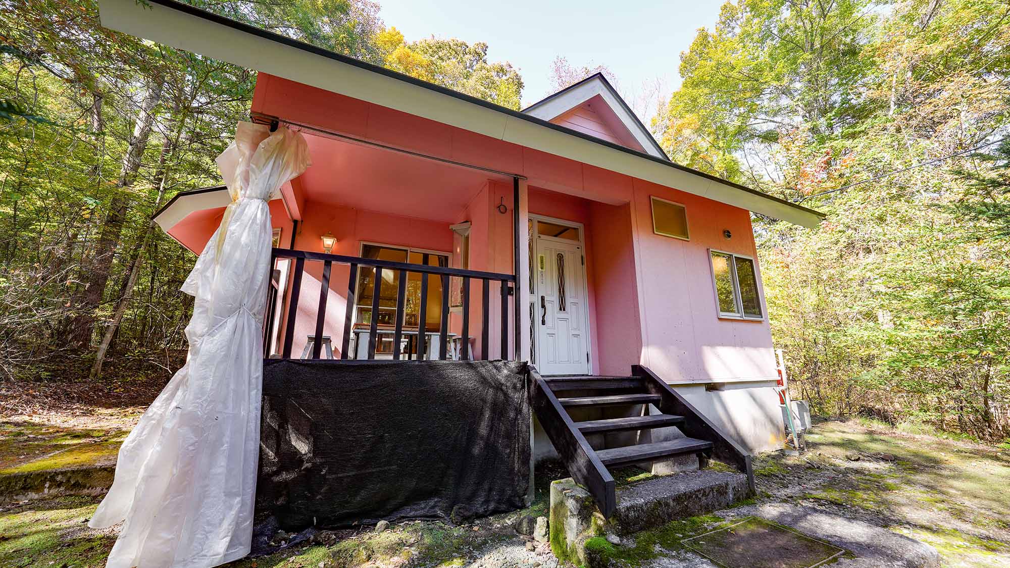 ・【エクセル】可愛らしいピンク色のコテージ。緑の中で際立つ独特な外観です