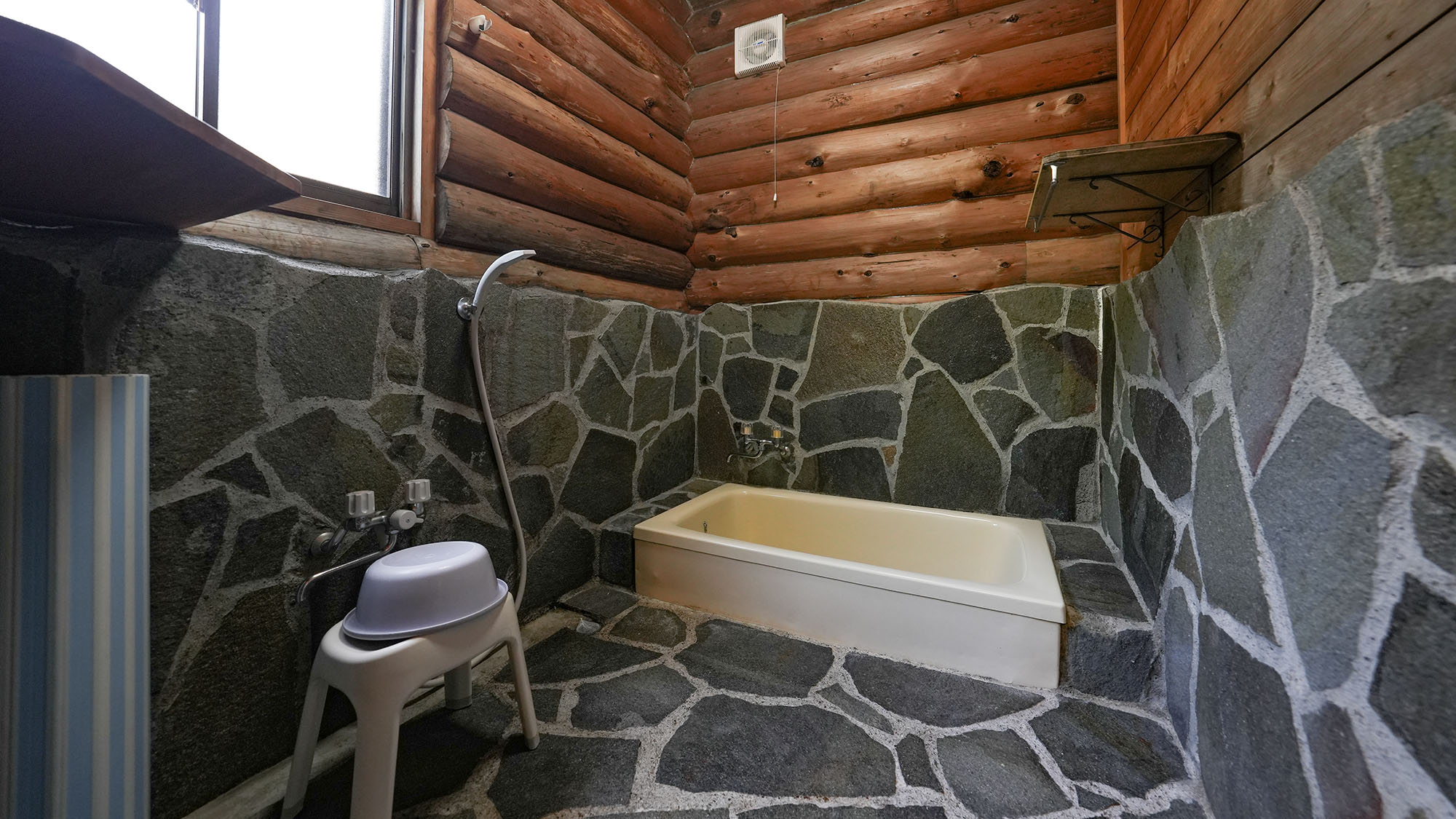 ・【カンパニュラ】個性的な石の壁や床が目を惹くバスルーム。ゆとりのある洗い場でのびのび洗うことが可能