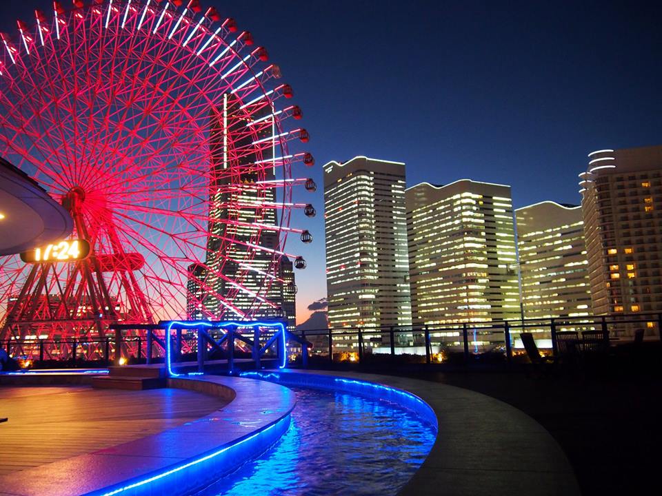 万葉倶楽部の展望足湯庭園の夜。青く光る足湯の向こうに、赤く光る観覧車とみなとみらいのビル