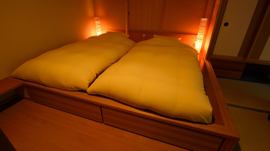 客室の寝具は小上がりの上にマットレス＋布団の和風ベッドでご用意しております。