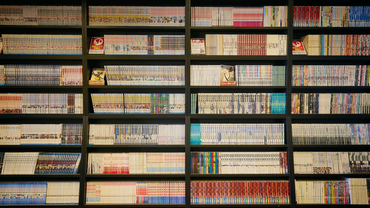 3S HOTEL ATSUGIのブックコーナー。黒い棚に漫画の単行本がずらりと並んでいる