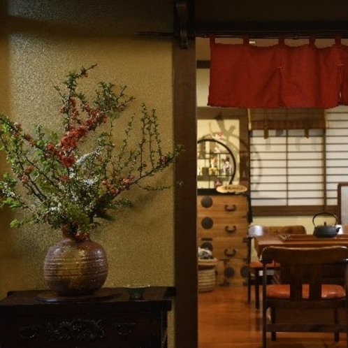 フロント横の生け花と奥は囲炉裏カフェ