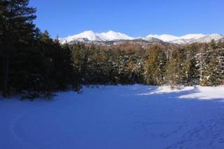冬、雪に覆われた牛止めの池と乗鞍岳