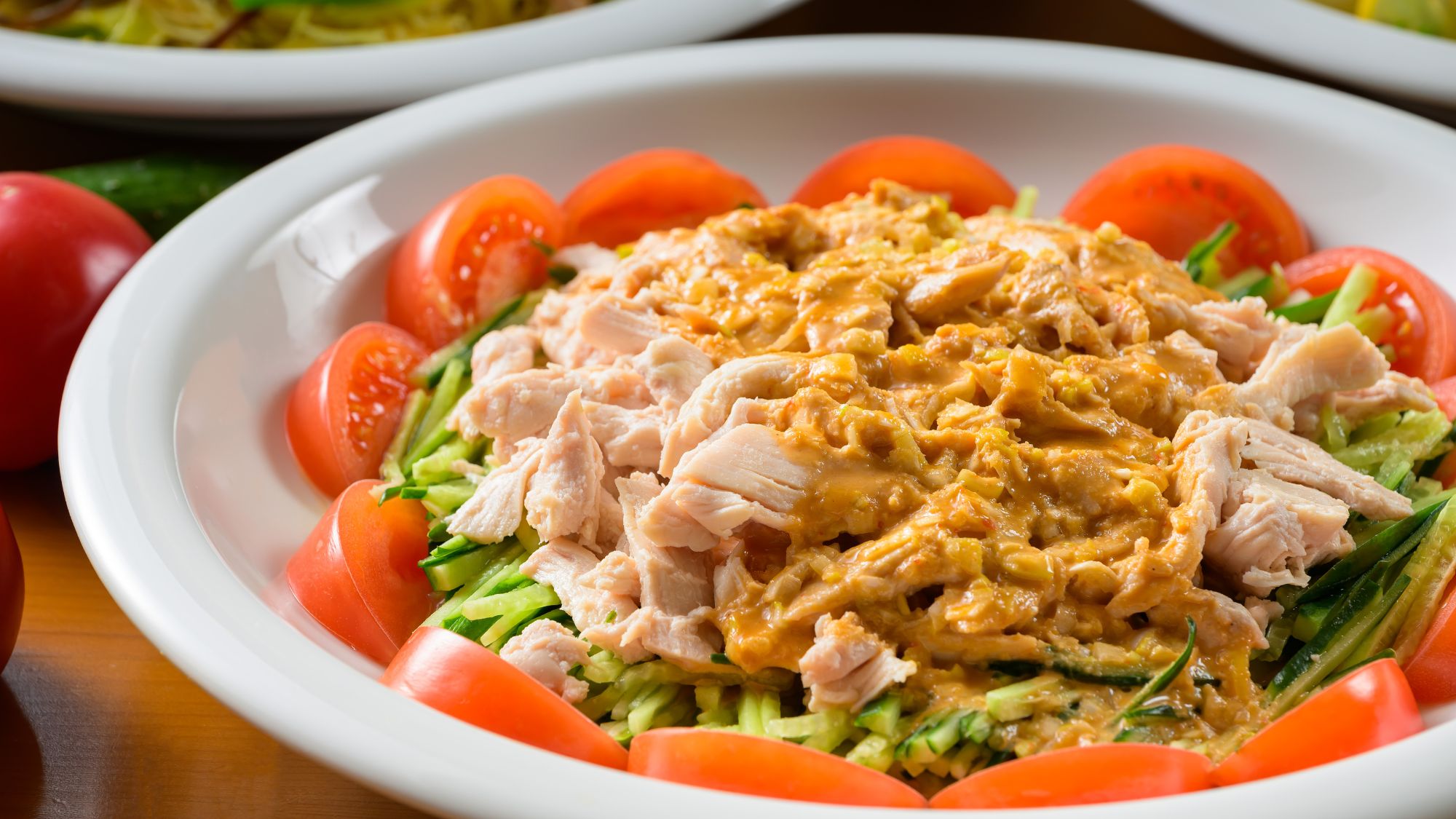 やわらかな蒸し鶏に香ばしい胡麻だれを合わせた中華の定番。夏野菜とともにさっぱりと楽しめる一皿です。