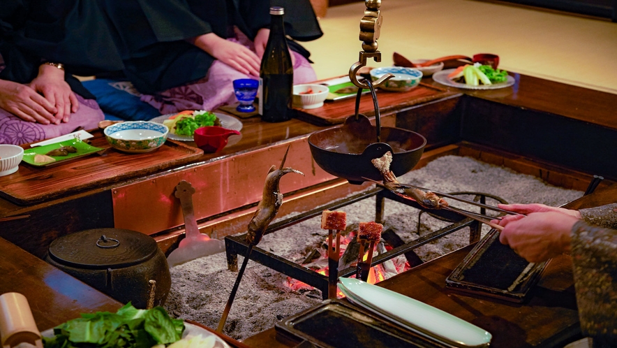夕食風景一例。盃を交わし、いろり炭火を交えながら芦名の料理をお楽しみください。