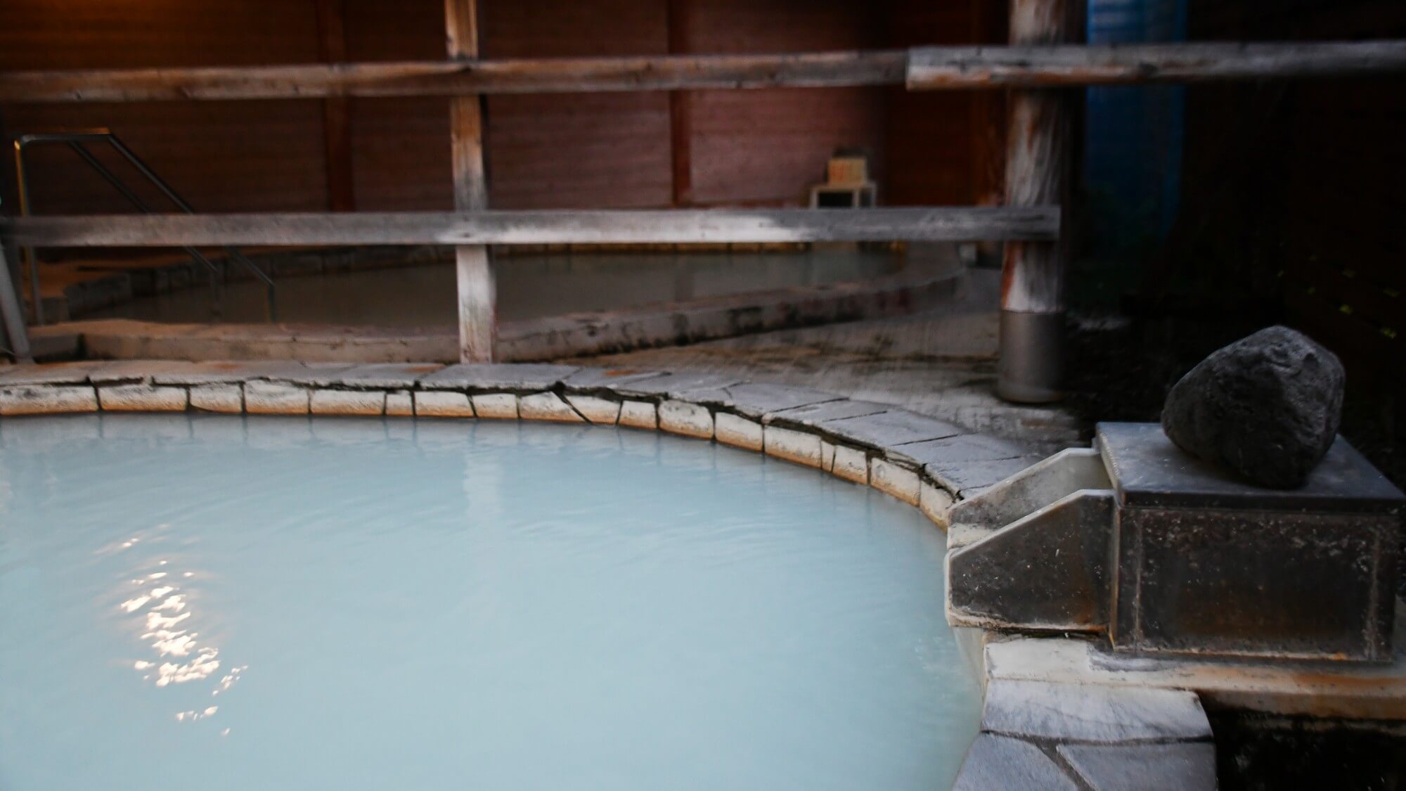 【1F硫黄泉・露天風呂】乳白色のお湯が日光が当たることで、青や薄緑など神秘的な色合いになります。