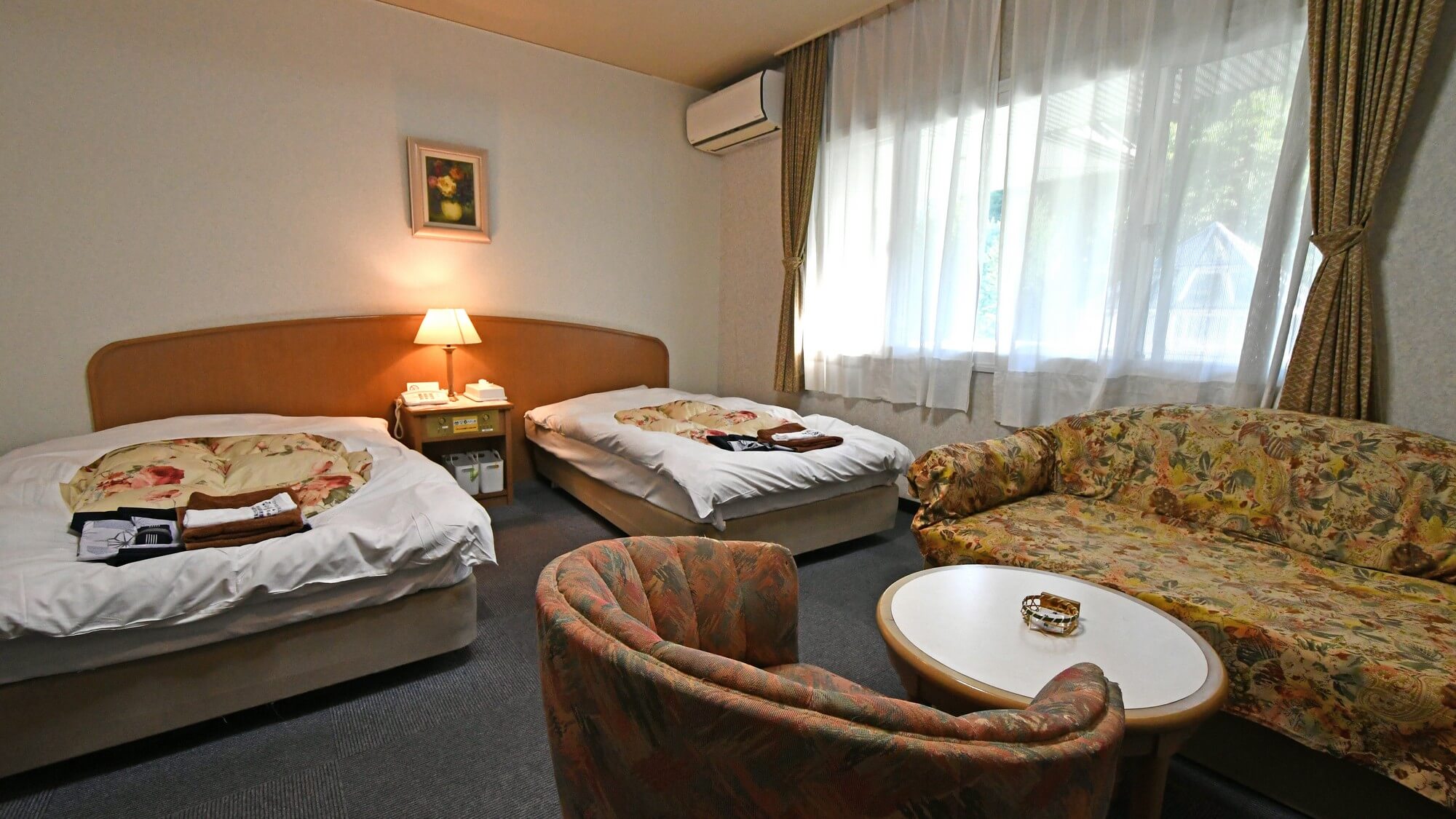 【洋室ツインルーム】ツインベッドを備えたゆったり洋室。ソファーセットでお寛ぎください。