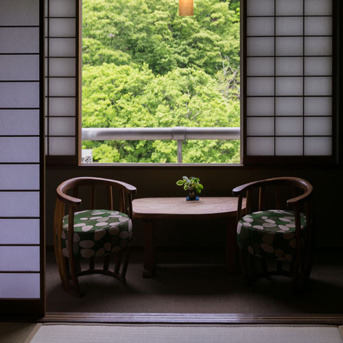 広縁の椅子に座って、外の景色を楽しんで　本館客室「10畳広縁付 」一例