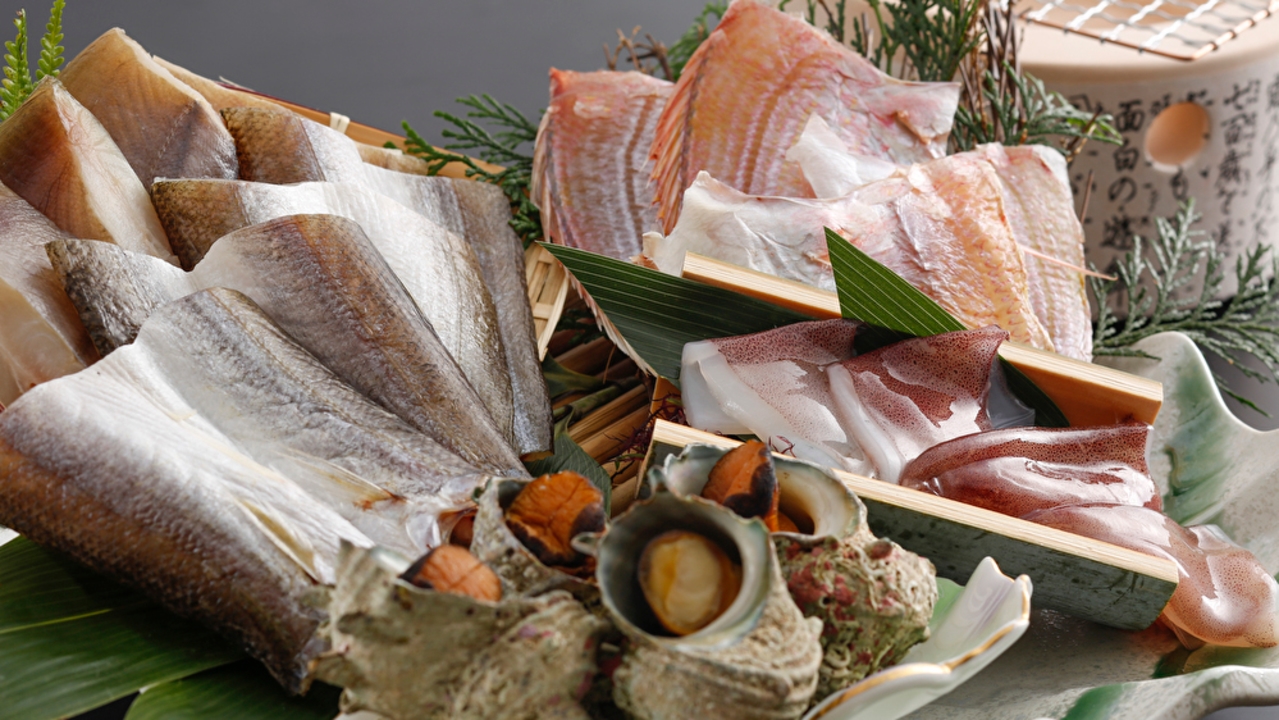 油屋本館の名物「海鮮炭火焼き」の盛り合わせ。干物や貝、刺身が並ぶ