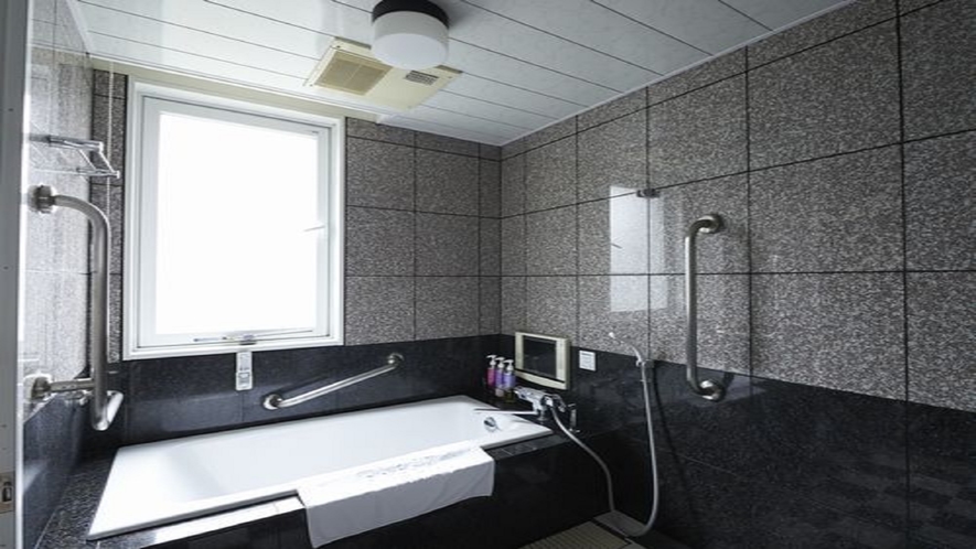 【ユニバーサルツインバスルーム】大きめのお風呂をご用意しております。小さなテレビ付き！