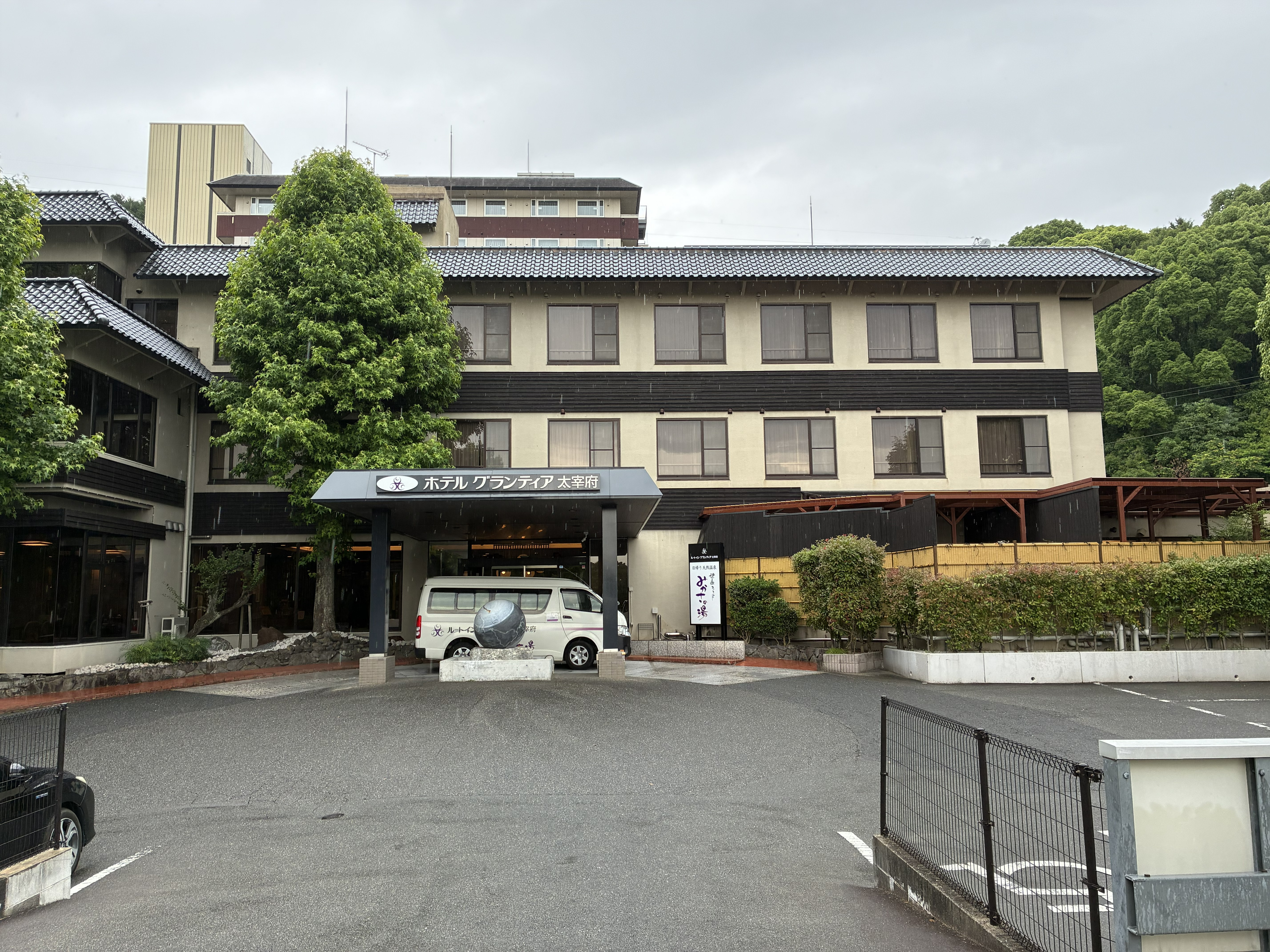 店舗外観の一枚でございます。店舗入口に見えますのは、太宰府駅とホテルを往復する無料のシャトルバスでございます。大自然の空間の中、疲れた身体と心を癒す施設でございます。