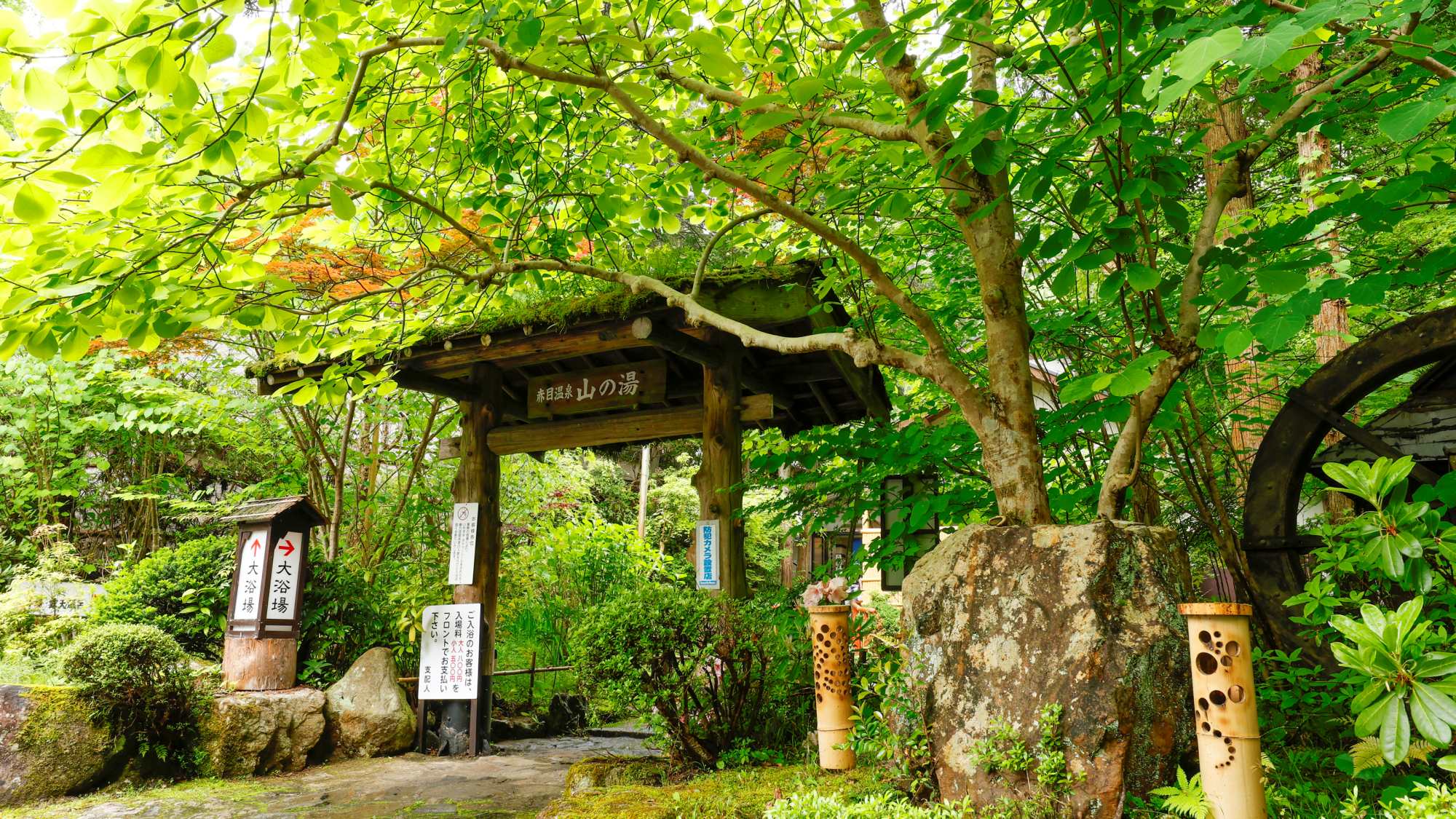 茅葺きの屋根が特徴的な「温泉入口」。広い敷地の園内を歩くのも楽しみのひとつ