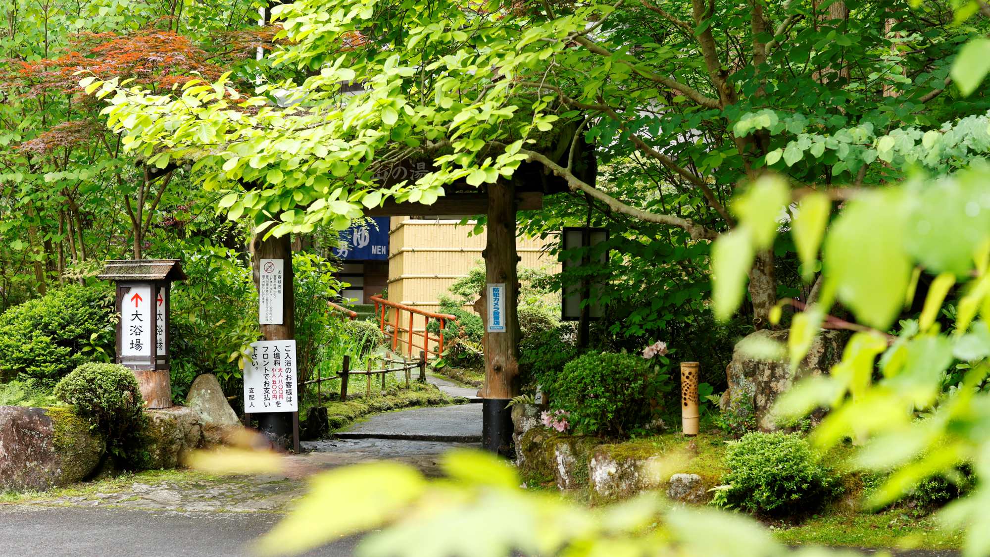 茅葺きの屋根が特徴的な「温泉入口」。広い敷地の園内を歩くのも楽しみのひとつ