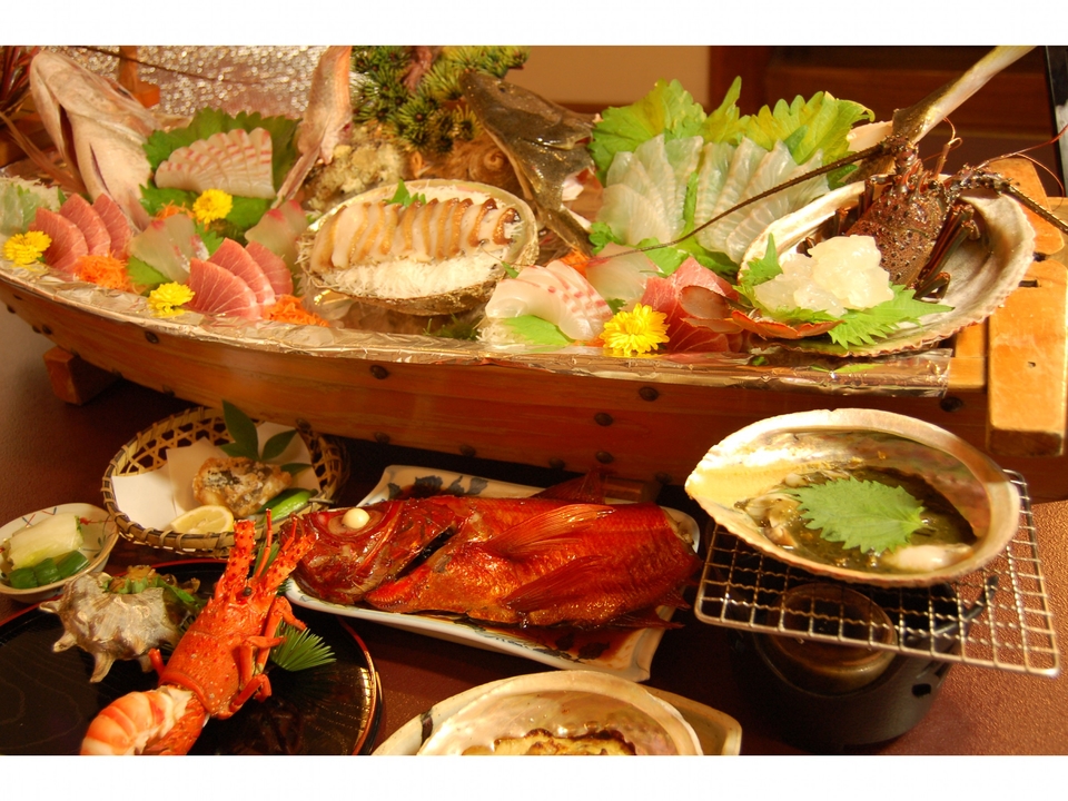 郷土料理の宿マタエムの夕食。刺身の舟盛りに金目鯛の煮付け、伊勢海老、あわびが並ぶ
