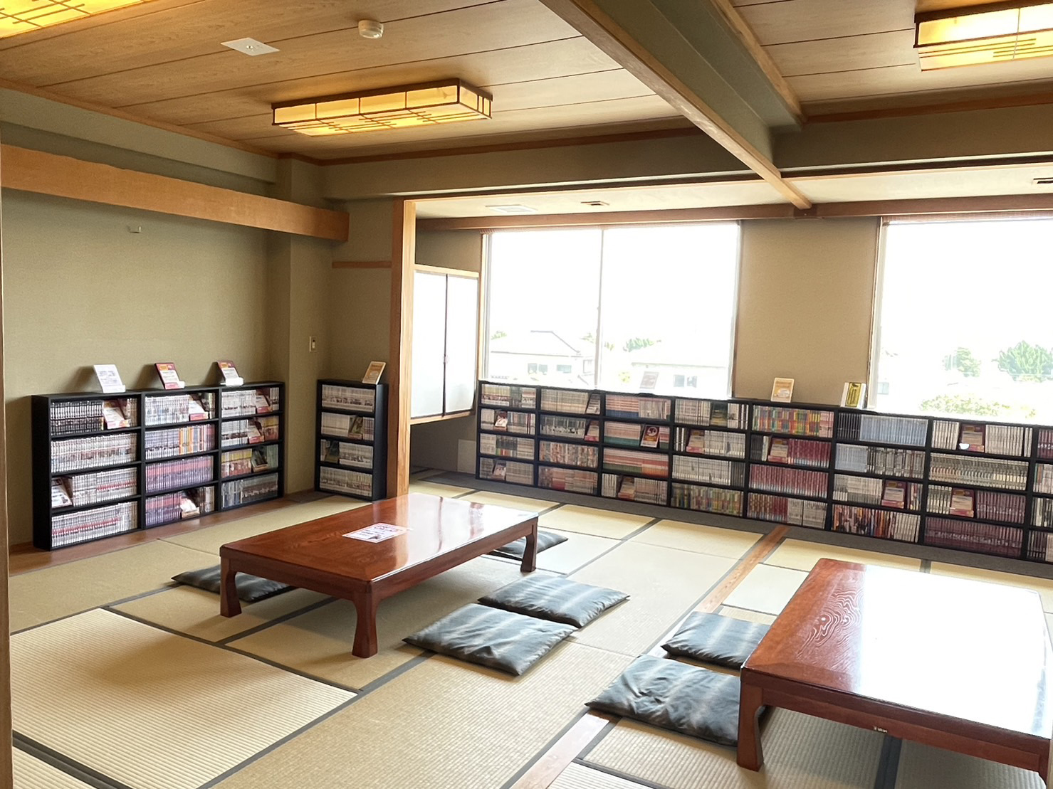 青松庭 白砂の漫画部屋。畳の和室に座卓と座布団が置かれ、窓ぎわの低い本棚に漫画が並んでいる