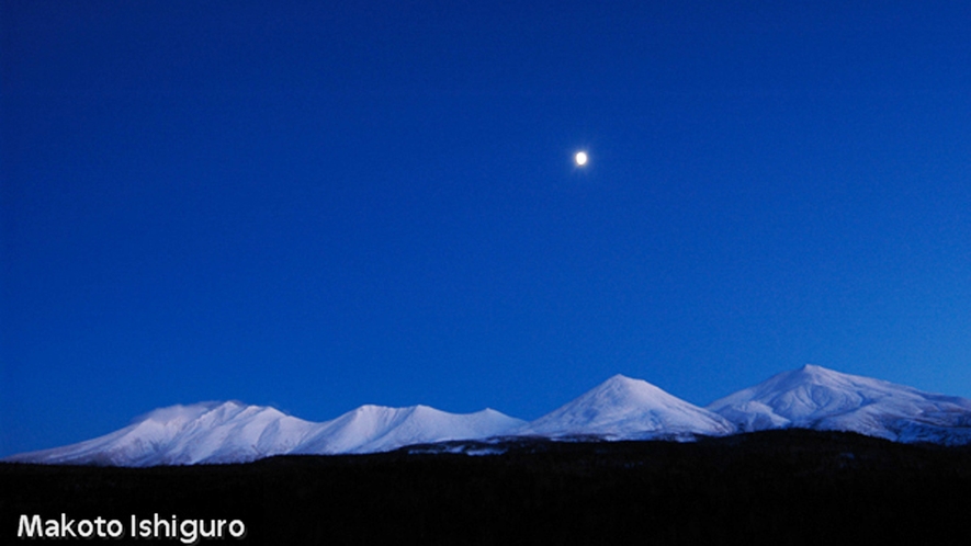 *富良野の月の夜空／夜の十勝岳連峰を照らすように輝く月。ここでしか見られない幻想的な風景。