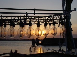 イカ釣り船のライトが夕日に染まる
