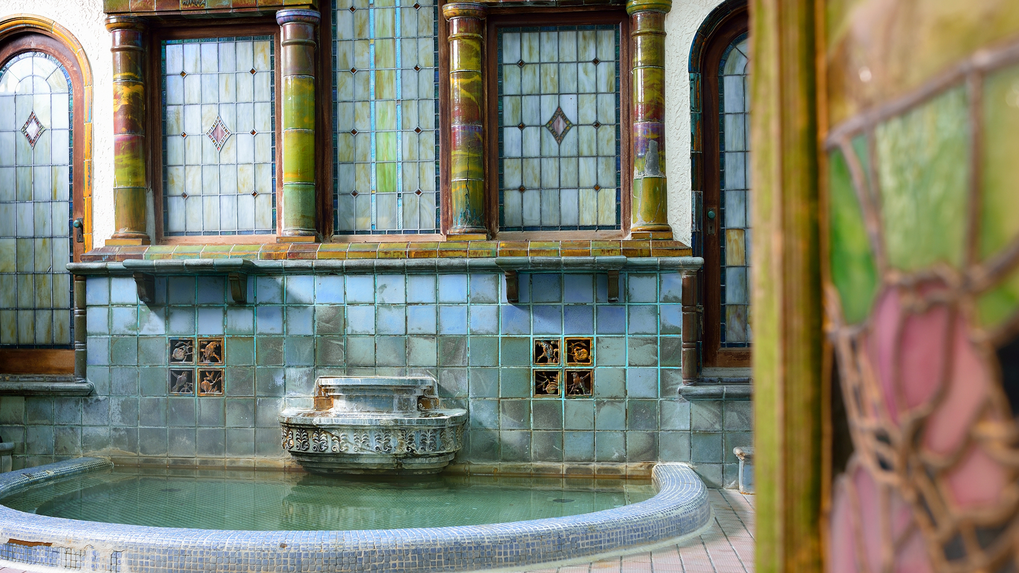 *【岩本楼ローマ風呂】入口のガラス戸のステンドグラスを開けると、古代ローマの馬蹄型浴槽が出迎えます。
