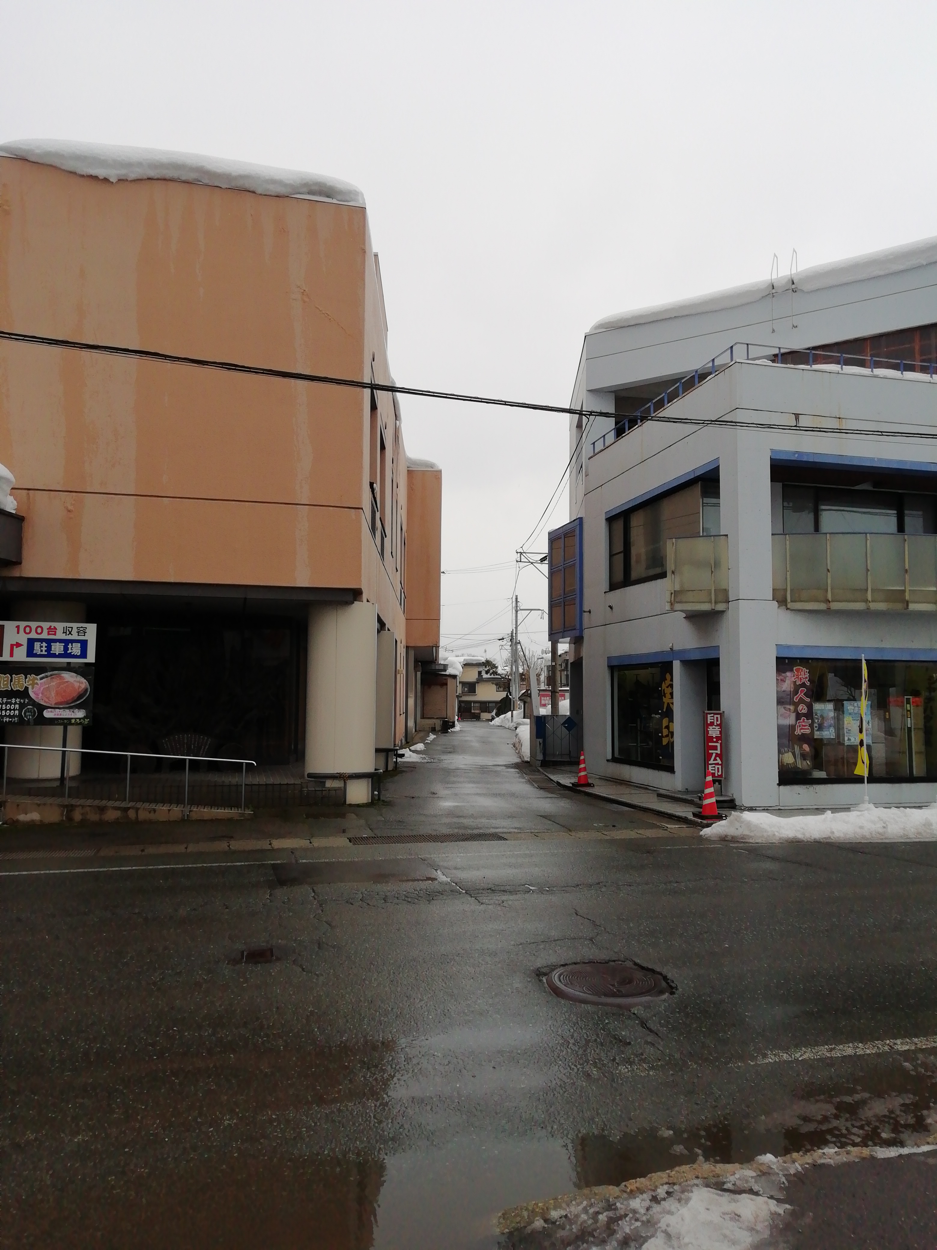 大地会館とはんこ販売店の間の路地を入る （大地会館ビルの脇を左折する）
